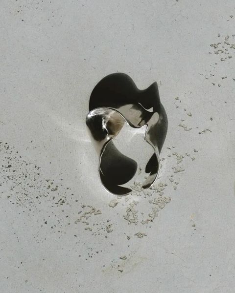 Silver ring with a unique design on a light gray surface