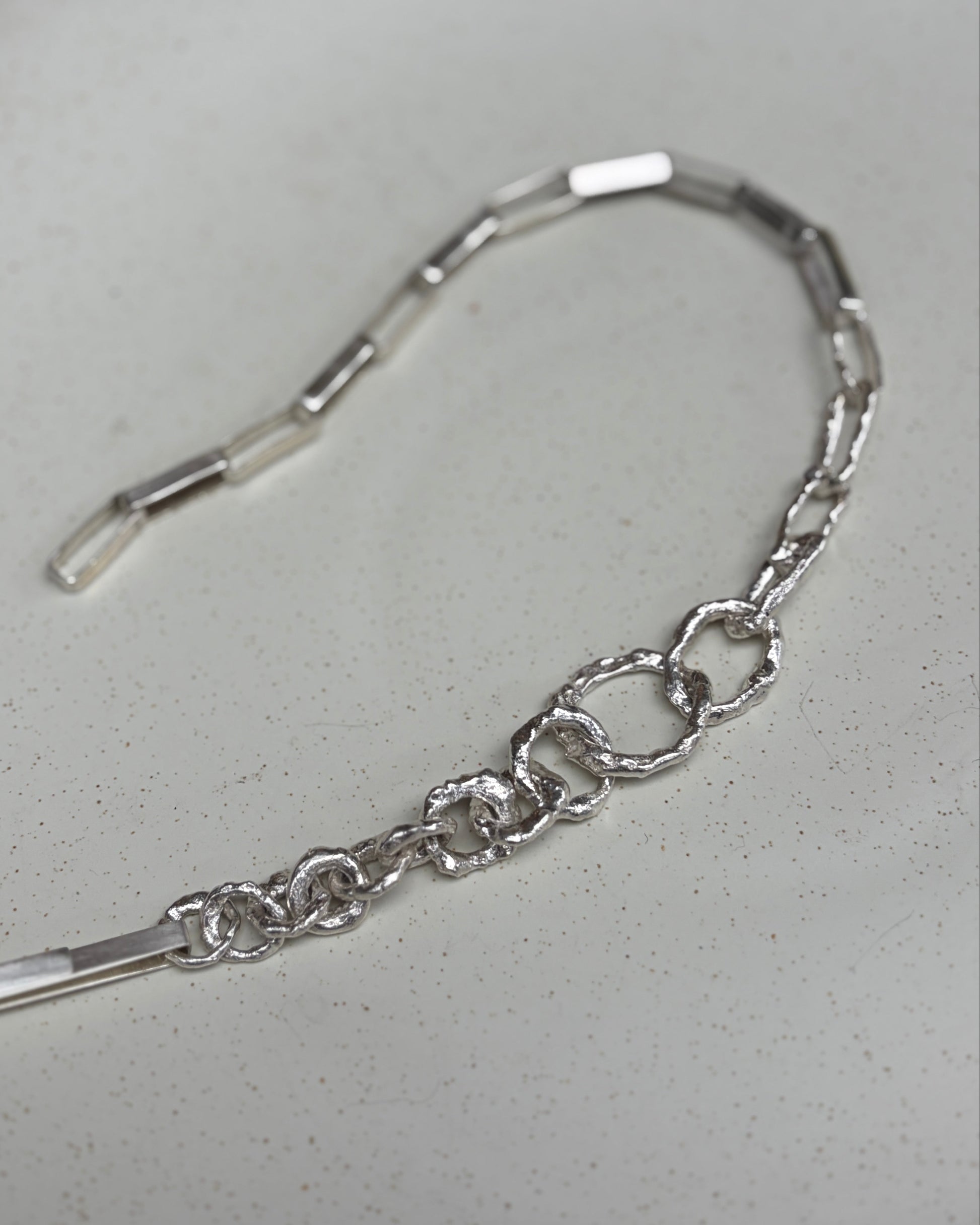 Textured silver chain on a white plate.