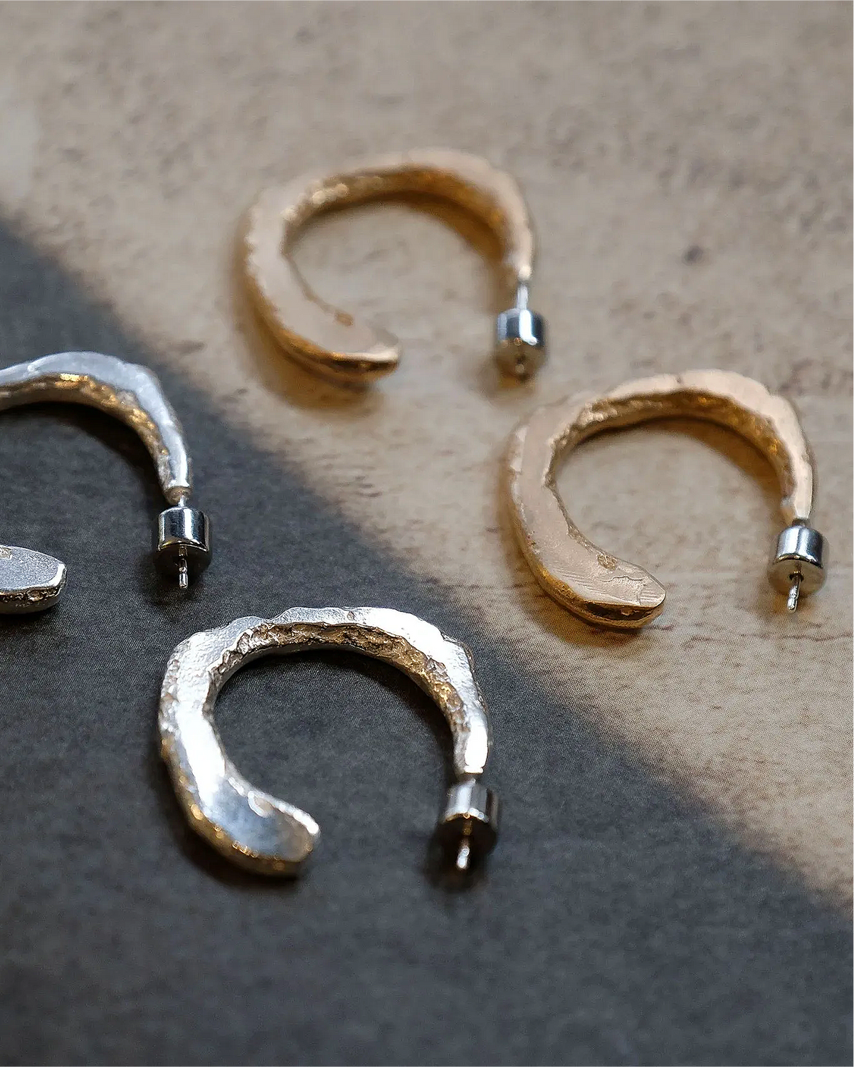 Set of silver and gold hoop earrings on a textured surface