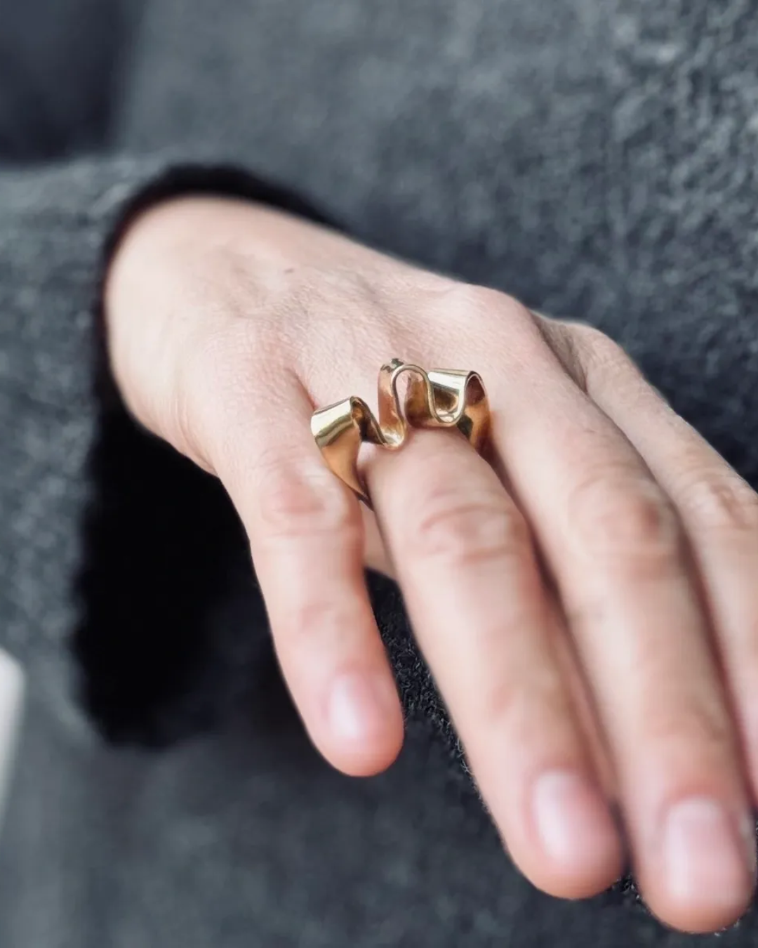 Gold ring on a finger against a dark background