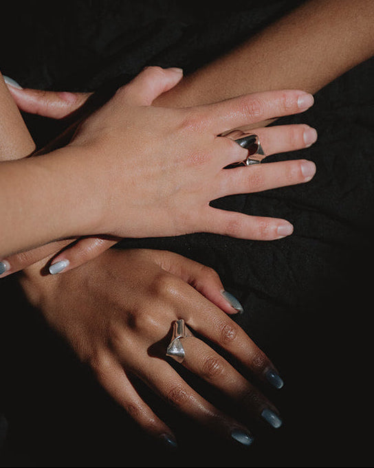 Hands across each other with silver rings 