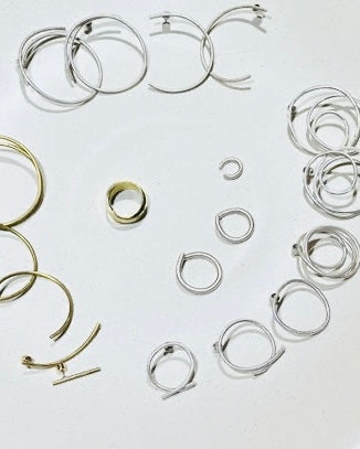 A set of minimalist, thin wire hoop earrings in both silver and gold finishes, arranged on a plain white background.