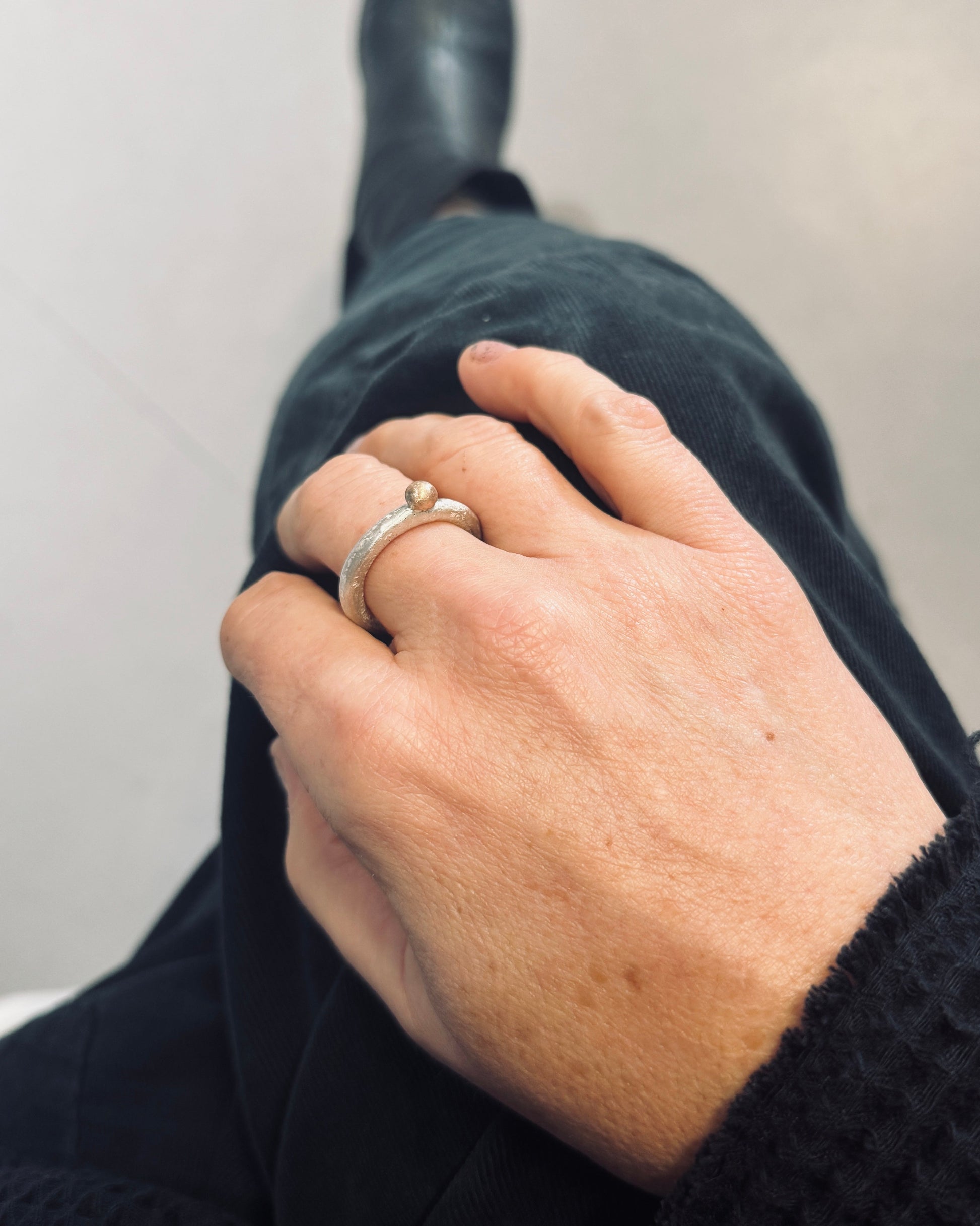 Close-up of a hand wearing two rings on a plain background