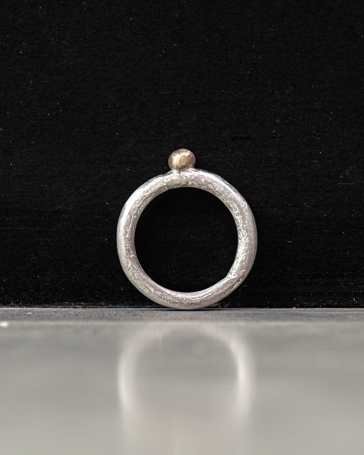 Silver ring with a small ball on a black background